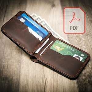 May include: A brown leather wallet with multiple card slots and a cash compartment. The wallet is open, revealing credit cards and cash. The stitching is visible around the edges. A PDF icon is in the upper right corner.