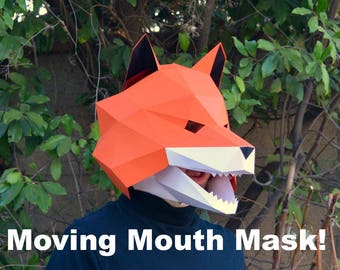 May include: A geometric orange fox mask with a moving mouth, black ears, and white teeth. The mask is made of folded paper and is worn by a person wearing a black shirt. The text "Moving Mouth Mask!" is at the bottom.