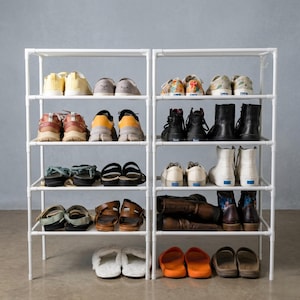 May include: A white ceramic mug with a black handle and the text "But First, Coffee" in a bold, black font. The mug is set against a neutral background, highlighting its simple design. The mug is approximately 4 inches tall.