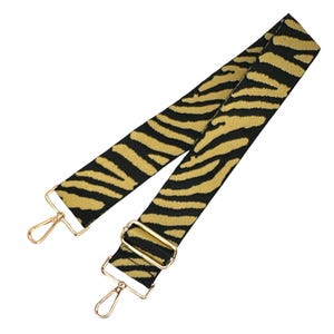 May include: A black and gold zebra print adjustable shoulder strap with gold metal clasps.