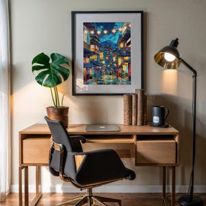 K&ouml;nnte beinhalten: Ein Holzschreibtisch mit einem schwarzen B&uuml;rostuhl, einem Laptop, einem gerahmten Druck einer Stadtstra&szlig;e mit Laternen, einer Topfpflanze und einer Stehlampe mit schwarzem Schirm.