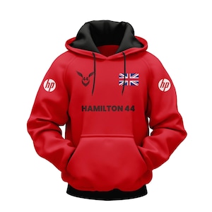 Peut inclure: Sweat à capuche rouge avec capuche et cordons noirs. Le texte "HAMILTON 44" et un drapeau britannique sont imprimés. Logos "hp" sur les manches.