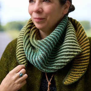 Puede incluir: Una bufanda tipo cuello tejida con textura acanalada y un degradado de color que transita del verde bosque profundo al verde lima brillante y amarillo dorado. El accesorio presenta un patrón de punto diagonal y un hilo suave y texturizado.