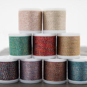 May include: A collection of ten spools of metallic thread in various colors, including gold, silver, red, green, blue, and purple. The spools are arranged in a pyramid shape.