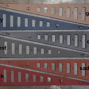 May include: Four leather straps with different colors and textures. The straps are cut in a triangular shape with holes and metal rivets. The colors are grey, navy, coal, and saddle. The text "grey", "navy", "coal", and "saddle" are written next to each strap.