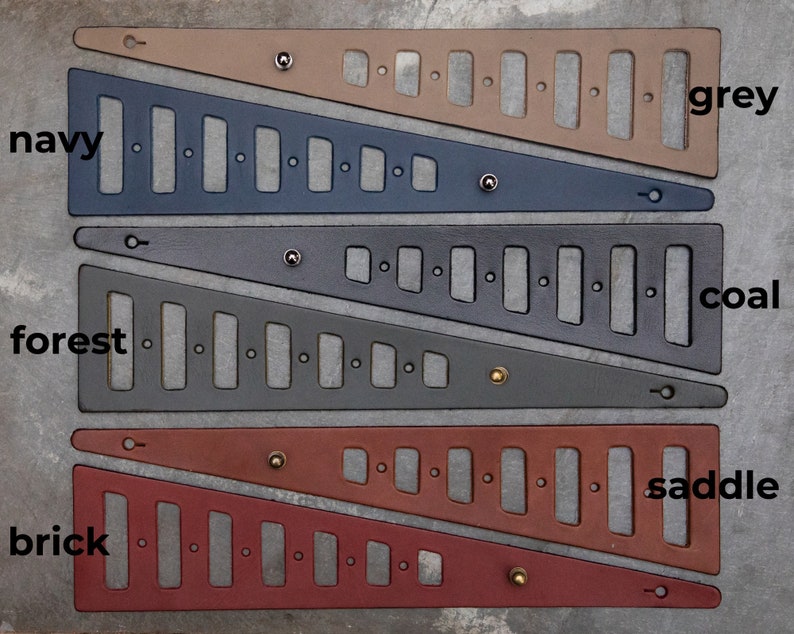 May include: Four leather straps with different colors and textures. The straps are cut in a triangular shape with holes and metal rivets. The colors are grey, navy, coal, and saddle. The text "grey", "navy", "coal", and "saddle" are written next to each strap.
