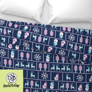 May include: A navy blue fabric with a repeating pattern of pink trees, white snowflakes, blue reindeer, and white snowmen with pink hats. The fabric is folded in half.