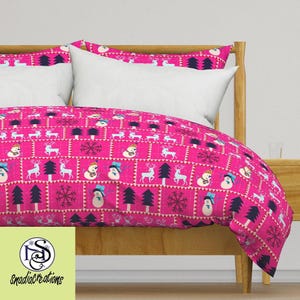 May include: Pink duvet cover with a winter holiday pattern featuring snowmen, reindeer, and pine trees. The pattern is repeated in a grid format.