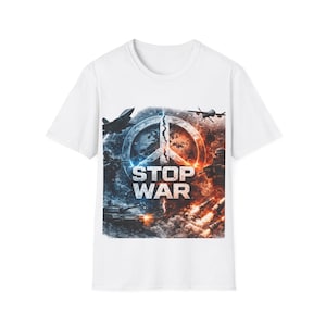 Puede incluir: Camiseta blanca con un diseño gráfico que representa un símbolo de la paz dividido por la mitad. El diseño incluye aviones militares, tanques y las palabras "STOP WAR". La obra de arte utiliza tonos azules, naranjas y grises.