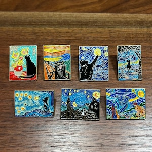 May include: A collection of seven enamel pins featuring black cats in various artistic styles. Each pin showcases a different painting, including sunflowers, a starry night, and a cat reaching for the moon. The pins are rectangular with vibrant colors.
