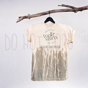 Może przedstawiać: Biała, wyblakła koszulka z efektem przetarcia. Koszulka ma okrągłe logo z napisem "handcrafted tee & shirts Wisconsin" i "bleached shirt mockup".