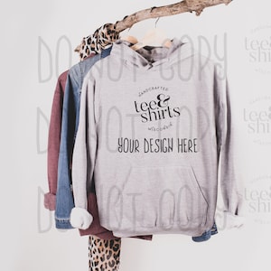 Op de afbeelding: Een grijs hoodie met een zak op de voorkant. De hoodie heeft de tekst "HANDCRAFTED tee&shirts WISCONSIN" en "YOUR DESIGN HERE" erop gedrukt.