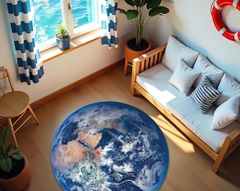 May include: A round rug featuring a detailed image of Earth, with continents and oceans in shades of blue, brown, and green. The rug is placed on a wooden floor in a room with a nautical theme, including a window with blue and white striped curtains.