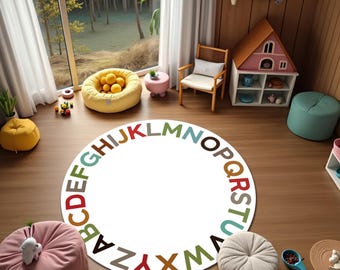 May include: A round white rug with the alphabet in various colors around the edge. The rug is in a child's playroom with a yellow beanbag chair, a pink ottoman, and a dollhouse.