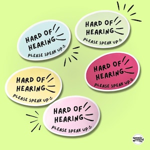 May include: Five oval stickers in pastel colours: light blue, light green, yellow, pink, and magenta. Each sticker has the text "HARD OF HEARING PLEASE SPEAK UP" in black. Black lines radiate from the words.