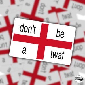 May include: A rectangular sticker with a white background and a red cross, like the English flag. The sticker has the words "don't be a twat" in black. Other similar stickers are blurred in the background.