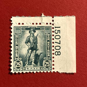 May include: A vintage 25-cent United States War Savings stamp. The stamp features a detailed illustration of a man in colonial attire holding a rifle. The stamp is teal and white with the text "United States" and "War Savings".