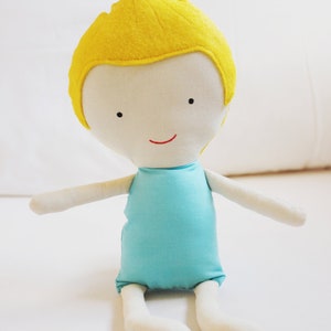 May include: A handmade doll with a yellow felt hairdo, a white face with embroidered features, and a light blue sleeveless dress.