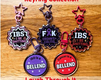 Peut inclure: Une collection de porte-clés en acrylique avec des textes humoristiques sur les maladies chroniques. Les porte-clés présentent diverses formes et couleurs, notamment rose, violet et rouge, avec des phrases comme "IBS I BE SHITTING".