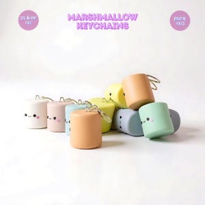 May include: A collection of colorful marshmallow-shaped keychains in various pastel colors, including white, pink, blue, yellow, peach, and mint green. Each keychain has a silver ring and a cute, smiling face. The text "MARSHMALLOW KEYCHAINS" is displayed above.