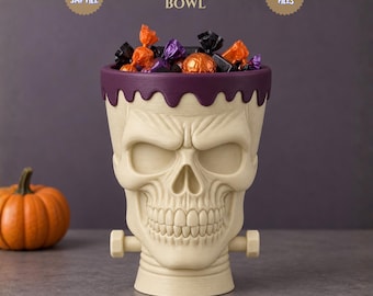 May include: A cream-colored skull bowl with a dark purple drip-style rim and two side bolts, resembling a Frankenstein monster. The bowl is filled with assorted wrapped candies. Text above reads: SKULL FRANKESTEIN BOWL, STL FILE, 3MF FILE, DIGITAL FILES.