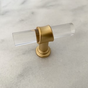 May include: A gold and clear acrylic cabinet knob with a T-shaped design.