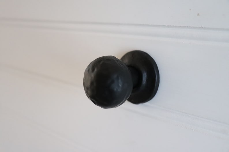 Puede incluir: Pomo de puerta negro con una manija redonda texturizada y una base circular plana.