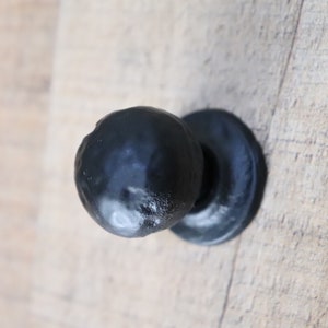 Puede incluir: Pomo de puerta redondo negro con base plana.