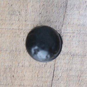 Puede incluir: Una sola trufa de chocolate negro sobre una superficie de madera.