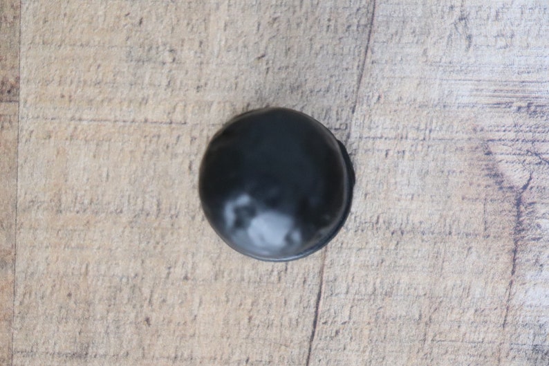 Puede incluir: Una sola trufa de chocolate negro sobre una superficie de madera.