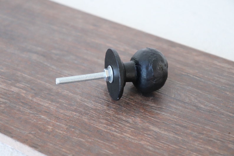 Puede incluir: Pomo de armario de metal negro con forma redonda y un tornillo para la instalaci&oacute;n.
