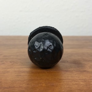 May include: Black cabinet knob with a textured, round design.