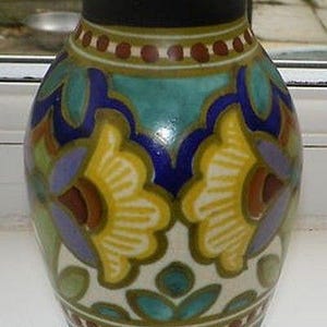 Puede incluir: Un jarrón decorativo de cerámica con borde y base negros. El jarrón presenta un colorido diseño floral con detalles en amarillo, azul y turquesa. El jarrón mide aproximadamente 25 cm de altura.