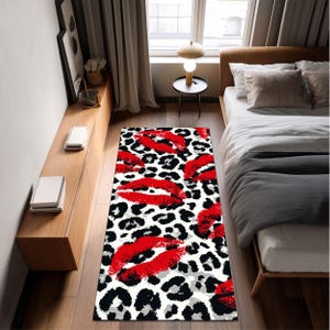 Op de afbeelding: Een rechthoekig tapijt met een luipaardprint in zwart, wit en grijs. Grote, felrode lippen zijn verspreid over het oppervlak van het tapijt, wat zorgt voor een gedurfd en stijlvol ontwerp. Dit tapijt is geschikt voor een slaapkamer of woonkamer.