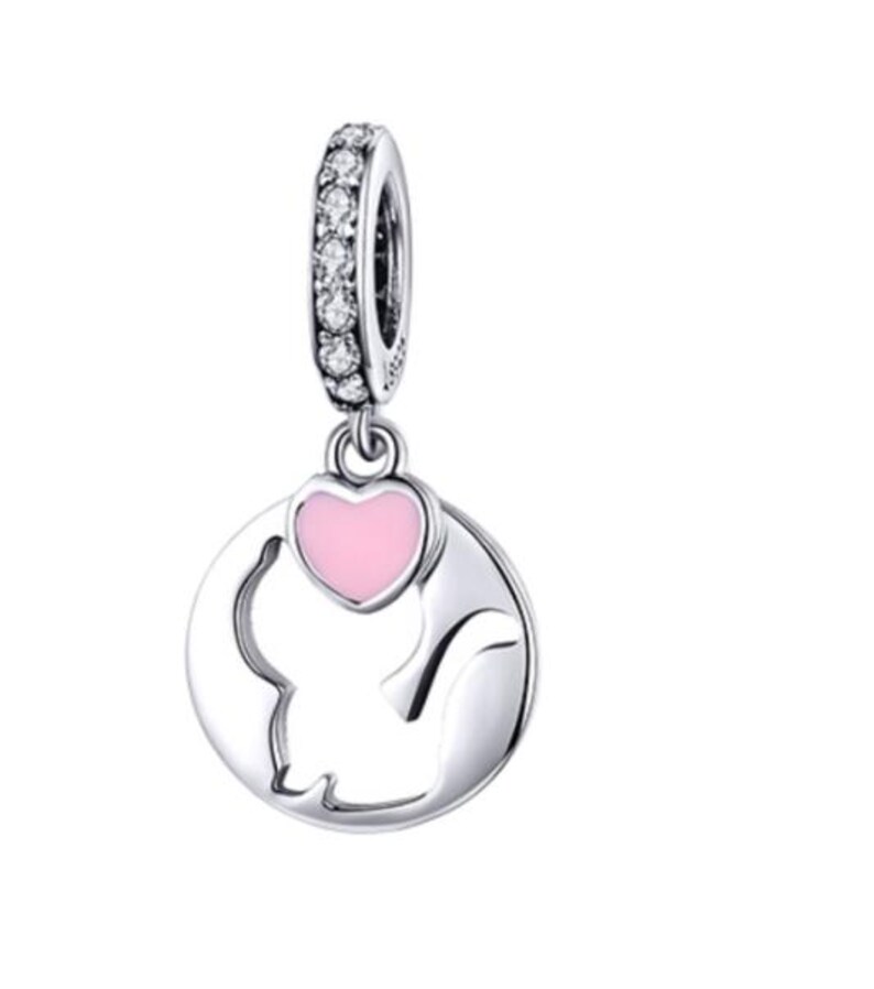 May include: A silver charm with a cat silhouette and a pink heart. The charm has a ring adorned with clear stones. The cat is inside a circular frame. A cute and charming piece of jewelry.