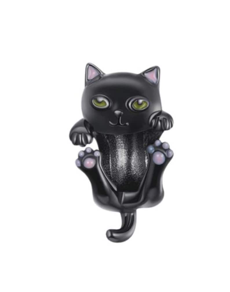 May include: A black cat figurine with green eyes and pink accents on the ears and paws. The cat is in a playful pose, with its paws outstretched and tail curled. The figurine has a glossy finish.