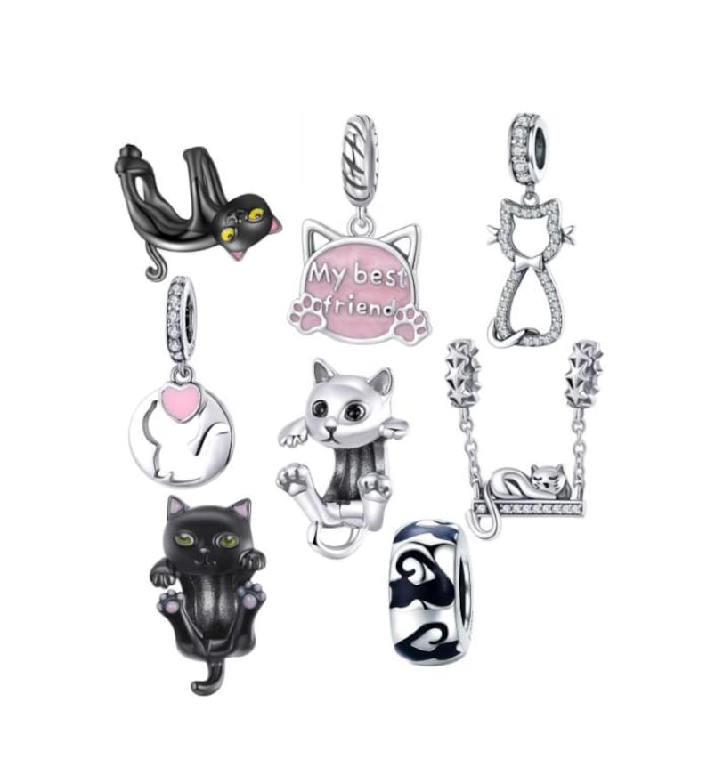 May include: A collection of silver cat-themed charms. The charms feature various cat designs, including a black cat, a cat on a swing, and a charm with the text "My best friend". Some charms have pink accents.