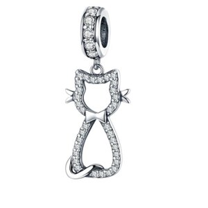 May include: A silver-colored cat charm with a bow tie, encrusted with clear crystals. The charm has a loop at the top, also adorned with crystals, for attaching to a bracelet or necklace. The cat's silhouette is detailed with sparkling stones.