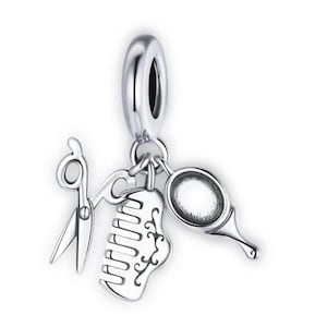 Könnte beinhalten: Ein silberner Charm-Anhänger mit einer Schere, einem Kamm und einem Handspiegel, die an einer Schlaufe hängen. Der Kamm hat ein dekoratives Design. Der Anhänger ist wahrscheinlich für ein Armband oder eine Halskette, passend zum Friseurhandwerk.