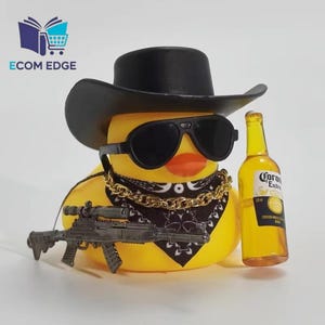 May include: A yellow rubber duck wearing a black cowboy hat, sunglasses, and a gold chain. The duck has a black bandana and is holding a toy rifle. A bottle of Corona beer is next to the duck.
