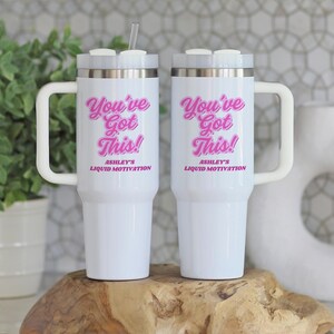 Personalized 40 oz tumbler with handle and straw featuring “You Got This” motivational message and custom name, held by woman in white sweater next to a snake plant. Custom iced coffee cup for women, ideal gift for her or office.