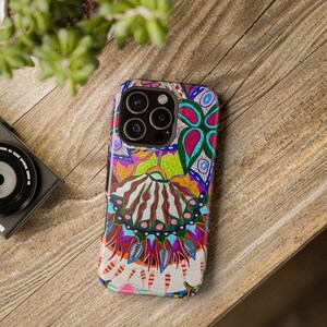 Puede incluir: Una funda de teléfono colorida con un diseño abstracto vibrante que presenta una mezcla de rojo, azul, verde, amarillo y blanco. La funda tiene un recorte para la cámara del teléfono.