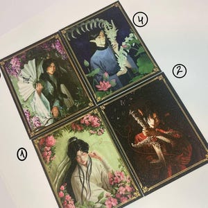 May include: Four rectangular art prints featuring illustrated figures in traditional-style clothing. Each print is framed by a gold border and numbered one through four. The illustrations depict characters with floral elements, fans, and swords in dark and light tones.
