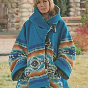 Puede incluir: Un abrigo con capucha turquesa con un estampado de inspiración suroeste en tonos naranja, azul y crema. El abrigo tiene un cierre de palanca y bolsillos grandes. Las mangas y la capucha están forradas con una tela en contraste.