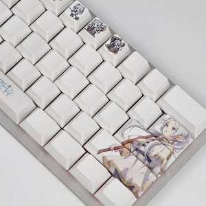 May include: A white mechanical keyboard with custom keycaps featuring anime-style illustrations. The keycaps have various anime character designs. The keyboard has a gray frame and white keycaps. The keycaps are square and evenly spaced.