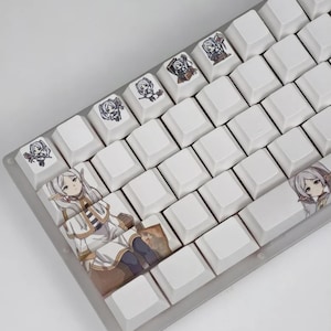 May include: White mechanical keyboard with custom keycaps featuring anime-style character illustrations. The keycaps have various designs, including full character portraits and smaller character icons. The keyboard has a clear, transparent frame.