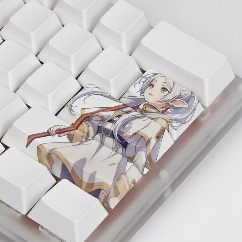 May include: A custom keyboard keycap featuring an anime-style illustration of a character with long white hair, wearing a white and gold outfit, and holding a staff. The keycap is surrounded by white keys.