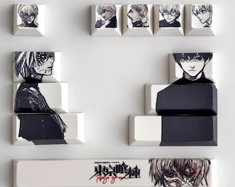 May include: A collection of custom keycaps featuring black and white anime-style illustrations. The keycaps display various character portraits and the title "Tokyo Ghoul" in Japanese and English. The keycaps are white with black artwork.