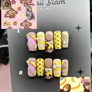 Può includere: Un set di unghie finte personalizzate a tema scimmia e banana. Le unghie presentano vari disegni, tra cui giallo con pois marroni, rosa con banane e marrone con una faccia di scimmia. Il testo "Nail Glam By Mel" è visibile.