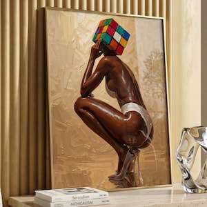 May include: A framed artwork depicts a person with a Rubik's Cube head, wearing a white bikini, and high heels. The painting is displayed on a beige wall, with a glass vase and books on a stone table. The books are titled "Surrealism" and "Aichicalism".